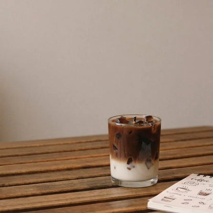 The coffee latte fragrance jar candle styled as a cozy, aesthetic decor accent piece on a modern study desk setup next to a book