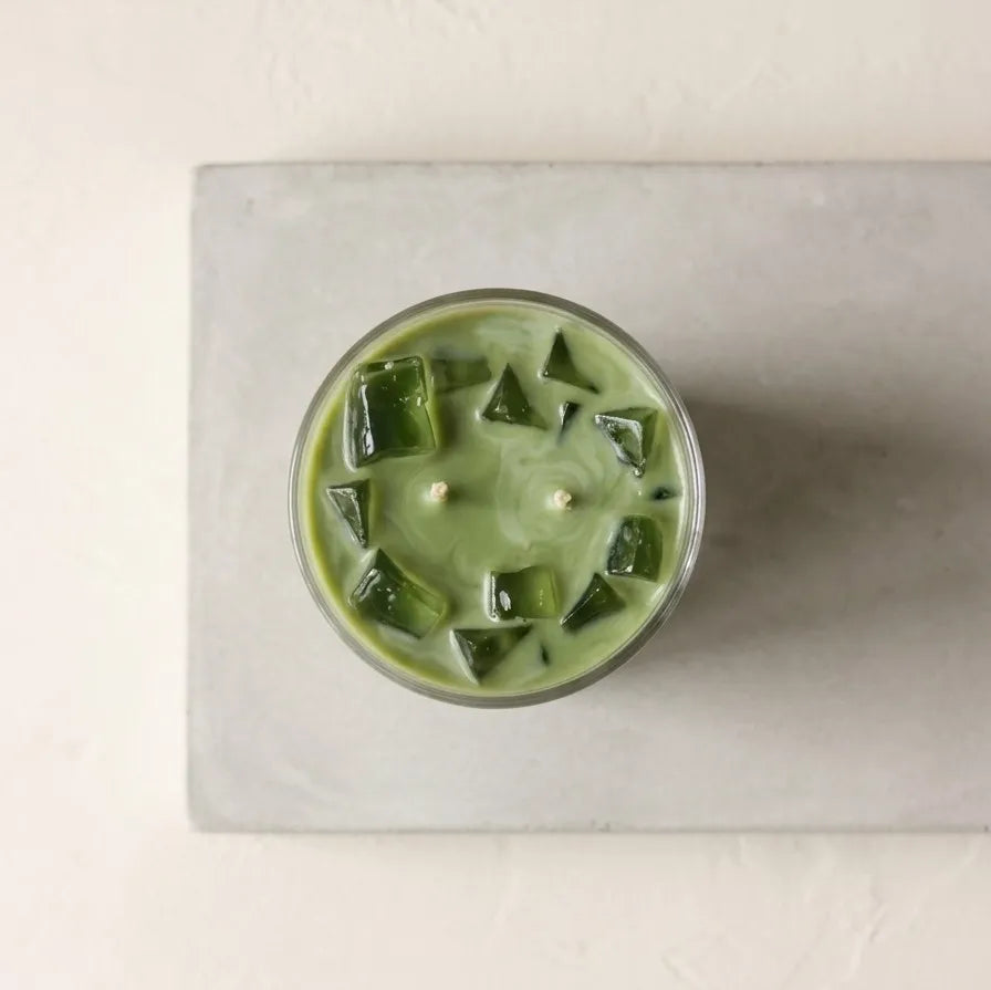 A lit iced matcha latte scented jar candle burning cleanly with a steady flame, releasing a soothing, creamy green tea fragrance into the room