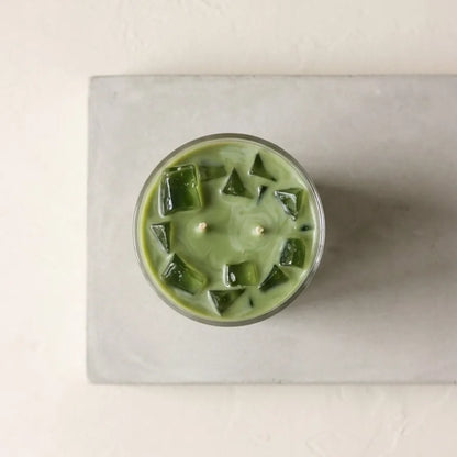 A lit iced matcha latte scented jar candle burning cleanly with a steady flame, releasing a soothing, creamy green tea fragrance into the room