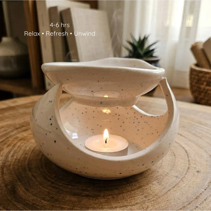A white ceramic diffuser lit by a warm tealight candle inside, casting soft shadows while melting an aromatherapy wax sachet on top