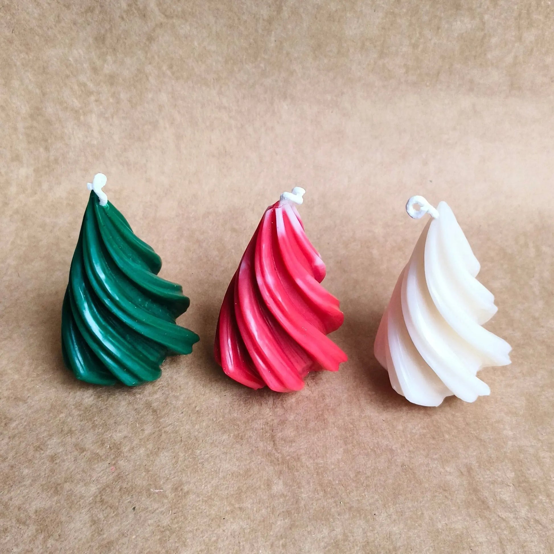 The geometric spiral Xmas tree candle displayed next to its premium minimalist gift box packaging, available for India
